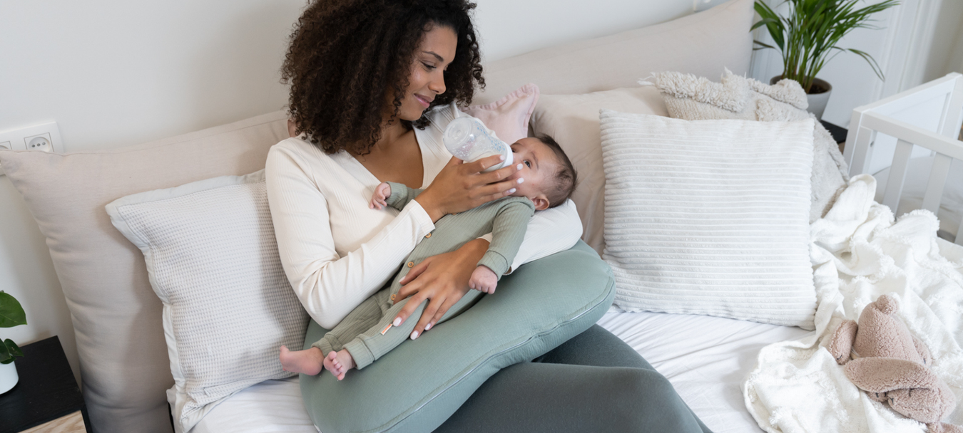 Doomoon Buddy imetys/raskaustyyny. Äiti syöttää vauvaa tuttipullosta.