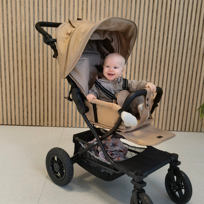 Hertta2 rattaat hiekan värisenä, lapsi istuu kyydissä