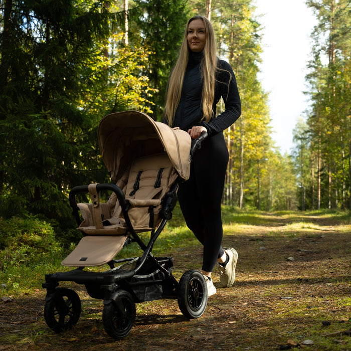 Hertta2 rattaat metsässä hiekka-värissä, nainen työntää