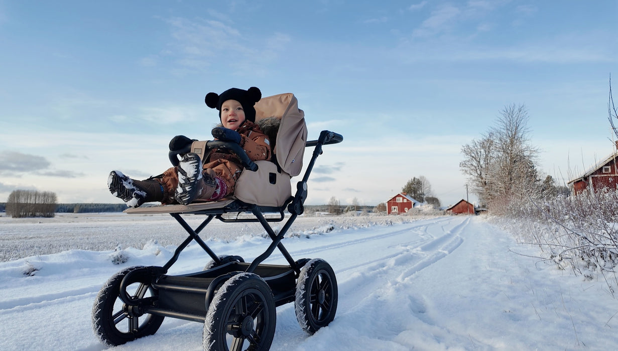 Ora Unto2 lastenrattaat kiinteillä renkailla lumimaisemassa lapsi kyydissä
