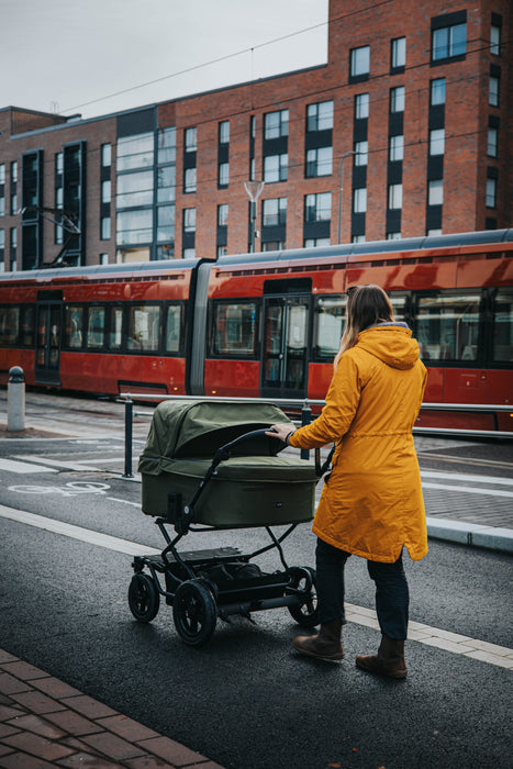 Ora Sisu kaksostenvaunut sammalen värisenä kaupunkimaisemassa