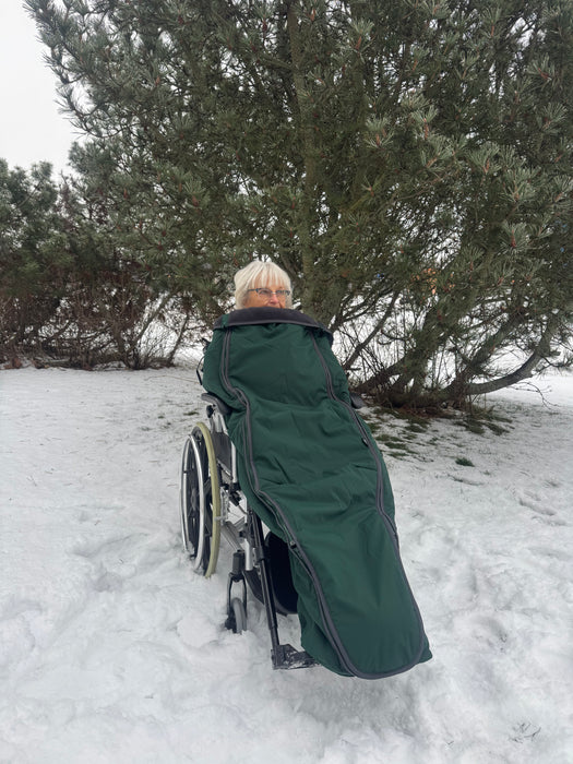 Nainen talvimaisemassa Oran pyörätuolin lämpöpussissa