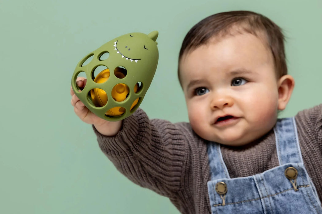 Trixie silikoninen pallohelistin (dino) vihreä kuvattuna vauvan kädessä